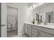 Bathroom featuring a double sink vanity, mirror, and a door to a walk-in closet at 409 Nix Ln, Lawrenceville, GA 30046