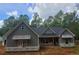 New construction home with gray siding, dark roof, and covered front porch is framed by surrounding trees and a bright blue sky at 879 Highway 101 N, Dallas, GA 30157