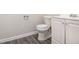 A bathroom with a white toilet, vanity, modern fixtures, and gray plank flooring at 535 Transit Cir, Atlanta, GA 30349