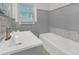 Updated bathroom featuring gray tile, a modern white vanity, and a bathtub with a shower at 2740 Pasco Se Ln, Atlanta, GA 30316