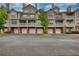 Exterior view of townhomes featuring a brick base, multiple balconies, and individual garages at 3107 Woodland Ln, Alpharetta, GA 30009
