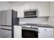 Well-equipped kitchen featuring stainless steel appliances and white cabinetry with black hardware accents at 3107 Woodland Ln, Alpharetta, GA 30009