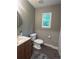 Bathroom featuring a vanity and sink with a round mirror, a standard toilet, and a large window at 3236 Grove Nw Trl, Acworth, GA 30101