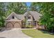 Charming two-story home featuring a well-manicured lawn, arched windows, and an attached two-car garage at 1336 Amberwood Dr, Woodstock, GA 30189