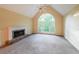 Large carpeted room featuring a fireplace, fan, and bright window for ample natural lighting at 1336 Amberwood Dr, Woodstock, GA 30189