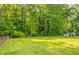 Expansive green backyard bordered by lush trees and a fence, with a storage shed in the distance at 2311 Cherry Blossom Sw Dr, Atlanta, GA 30331