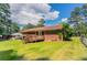 Back exterior view of a brick house with a deck and a spacious lawn under a blue sky at 2311 Cherry Blossom Sw Dr, Atlanta, GA 30331