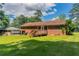 Back exterior view of a brick house with a deck and a spacious lawn under a blue sky at 2311 Cherry Blossom Sw Dr, Atlanta, GA 30331