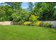 Backyard view of the large manicured lawn, wooden fence, and mature trees at 450 Hammersmith Dr, Suwanee, GA 30024