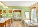 Bright main bathroom with double sinks, soaking tub, separate shower, and bold green walls at 450 Hammersmith Dr, Suwanee, GA 30024
