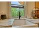 A close up of the kitchen sink shows a bright window and light colored counter tops at 60 Browning Shoals Rd, Social Circle, GA 30025