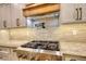 Close-up of a gas range with stone backsplash and custom wooden range hood at 60 Browning Shoals Rd, Social Circle, GA 30025