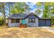 Charming bungalow featuring a brick exterior, dark roof, and a vibrant teal front door at 1554 Cardinal Rd, Jonesboro, GA 30238