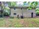 The back exterior with the stone base and a plain upper story, set within a lush green yard with mature trees at 2952 Mcafee Rd, Decatur, GA 30032