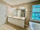Bathroom with a double sink vanity, soaking tub, and a window for natural light at 3650 Deep Cove Dr, Cumming, GA 30041