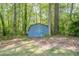 Charming blue storage shed nestled among lush trees in the backyard, adding practical outdoor storage at 554 Cana Of Galilee Ct, Tucker, GA 30084