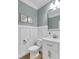Stylish half bathroom features wainscoting, modern vanity, framed art and sleek mirror at 4240 Spring Ridge Dr, Cumming, GA 30028