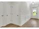 Hallway featuring wood floors, white trim, paneled walls, multiple doors, and contemporary lighting at 4240 Spring Rdg, Cumming, GA 30028