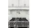 Close-up of stainless steel cooktop with pot filler faucet and modern backsplash at 4370 Freys Farm Nw Ln, Kennesaw, GA 30152