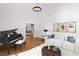 Inviting living room with hardwood floors, white sofas, a piano, and natural light streaming through large windows at 4370 Freys Farm Nw Ln, Kennesaw, GA 30152