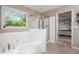 Bright bathroom features a soaking tub under a window and a glass-enclosed shower at 4614 Riveredge Cv, Snellville, GA 30039