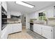 Galley kitchen featuring white cabinets, stainless appliances, granite counters, and updated flooring at 6659 Manoleta Dr, Lithonia, GA 30038
