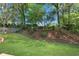 Expansive backyard featuring manicured lawn, mature trees, and a charming wooden fence along the property line at 1555 Heritage Trl, Roswell, GA 30075
