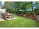 Secluded backyard with a spacious lawn, stone patio, and outdoor seating, perfect for relaxing and entertaining at 1555 Heritage Trl, Roswell, GA 30075