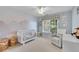 Cozy Bedroom with crib, rocking chair, and soft mountain mural, bathed in gentle light from the window at 1555 Heritage Trl, Roswell, GA 30075