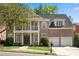 Charming brick home featuring a columned front porch and balcony with manicured landscaping at 1555 Heritage Trl, Roswell, GA 30075