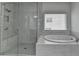 Luxurious bathroom with a glass shower and a separate soaking tub with marble tiling throughout at 3180 Andover St, Cumming, GA 30028