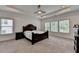Spacious bedroom with tray ceilings, a ceiling fan, and large windows overlooking a lush outdoor area at 3180 Andover St, Cumming, GA 30028