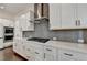 Kitchen featuring a cooktop, range hood, white cabinets, gray backsplash, and marble countertops at 3180 Andover St, Cumming, GA 30028