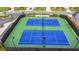 Aerial view of green and blue tennis courts in a fenced community with lighting and landscaping at 3180 Andover St, Cumming, GA 30028