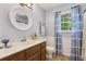 Bathroom features a wood vanity, stylish mirror, and window with bright curtains at 3876 Winners Ct, Marietta, GA 30062