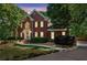 Stately brick home featuring a manicured lawn, mature trees, and elegant architectural details at 5100 Sunset Maple Trl, Lilburn, GA 30047