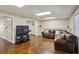 Cozy living room with polished concrete floors, a plush leather sofa, and a large TV for entertainment at 5100 Sunset Maple Trl, Lilburn, GA 30047