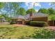 Spacious brick home featuring a patio, lush green lawn, and mature trees at 225 Wexford Overlook Dr, Roswell, GA 30075