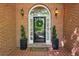 Elegant front door with sidelights, decorative wreath, and stylish potted plants at 225 Wexford Overlook Dr, Roswell, GA 30075