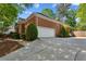 Side view of a brick home with an attached two-car garage and driveway at 225 Wexford Overlook Dr, Roswell, GA 30075