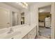 Bright bathroom with a dual sink vanity and a doorway leading to a kitchen area at 3855 Greenside Ct, Dacula, GA 30019