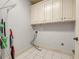 Functional laundry room features white tiled floors and ample above storage cabinets at 3855 Greenside Ct, Dacula, GA 30019