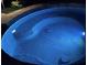 Sparkling inground pool features bright blue lighting and a serene ambiance for nighttime enjoyment at 3855 Greenside Ct, Dacula, GA 30019