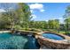 Beautiful pool and stone hot tub with waterfall features and lush greenery at 3855 Greenside Ct, Dacula, GA 30019