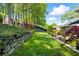 Spacious backyard with a stone retaining wall, lush greenery, and a charming seating area at 5452 Tally Green Dr, Marietta, GA 30068