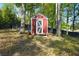 Quaint red storage shed with white trim, nestled among mature trees in the backyard at 5452 Tally Green Dr, Marietta, GA 30068