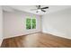 Spacious bedroom with hardwood floors, ceiling fan, and a large window offering a tranquil view at 5705 Twelve Oaks Dr, Cumming, GA 30028