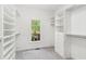 Bright walk-in closet features a window and custom white shelving for optimal storage and organization at 5705 Twelve Oaks Dr, Cumming, GA 30028