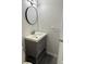 Bathroom vanity features a round mirror, modern light fixture and a gray cabinet with a white countertop and gray flooring at 2080 Charter Ln, Lithonia, GA 30058