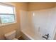Bright bathroom featuring a white tiled shower-tub and a window overlooking the neighborhood at 570 Eldridge Dr, Suwanee, GA 30024